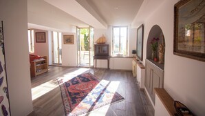 Un vaste espace de vie agrémenté d’un grand tapis, de meubles en bois et d’un téléviseur.