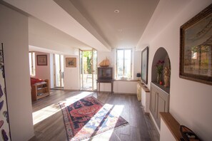 Un vaste espace de vie agrémenté d’un grand tapis, de meubles en bois et d’un téléviseur.