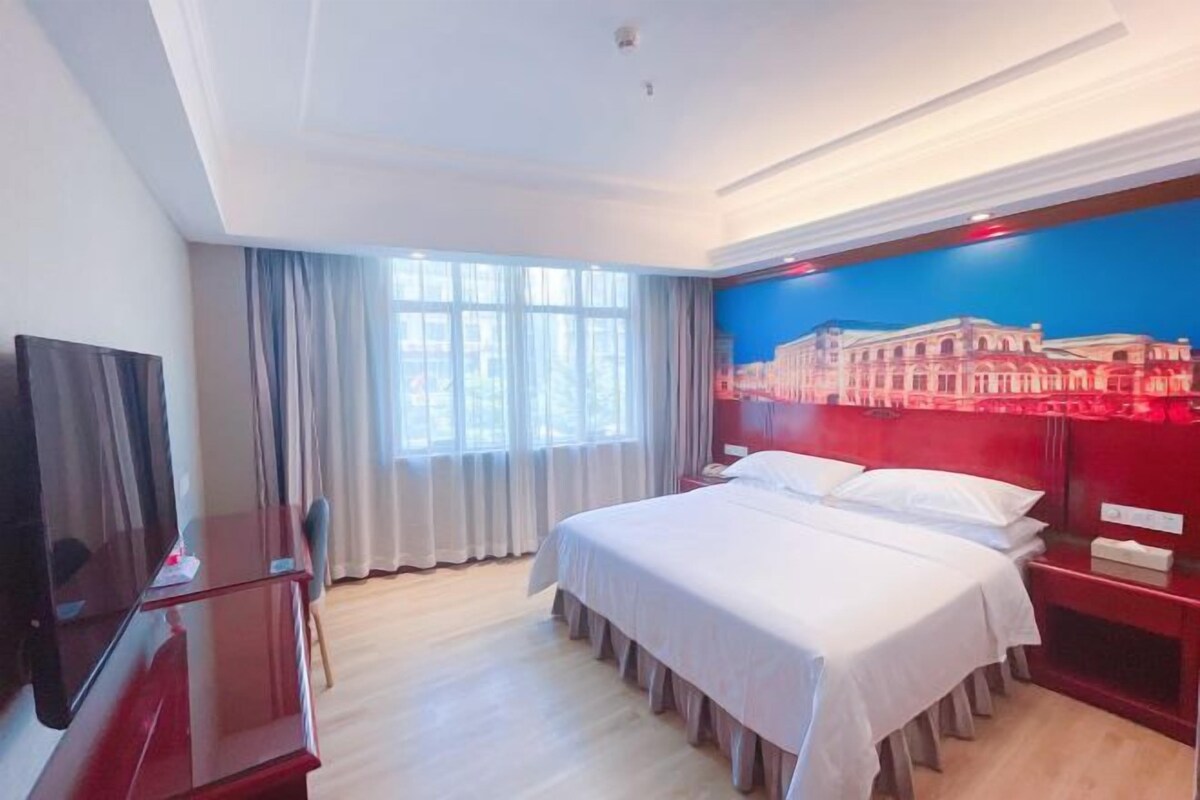 Habitación de hotel con cama, televisor, escritorio y un cuadro en la pared.