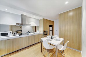 A modern kitchen with a dining area, featuring a white countertop, wooden cabinets, and a built-in oven.