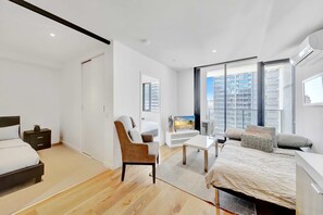 Une chambre moderne avec un lit, une chaise, un téléviseur et une grande fenêtre donnant sur la ville.