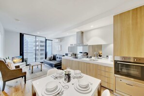 Una cocina moderna con comedor, horno empotrado y vistas a la ciudad a través de amplias ventanas.