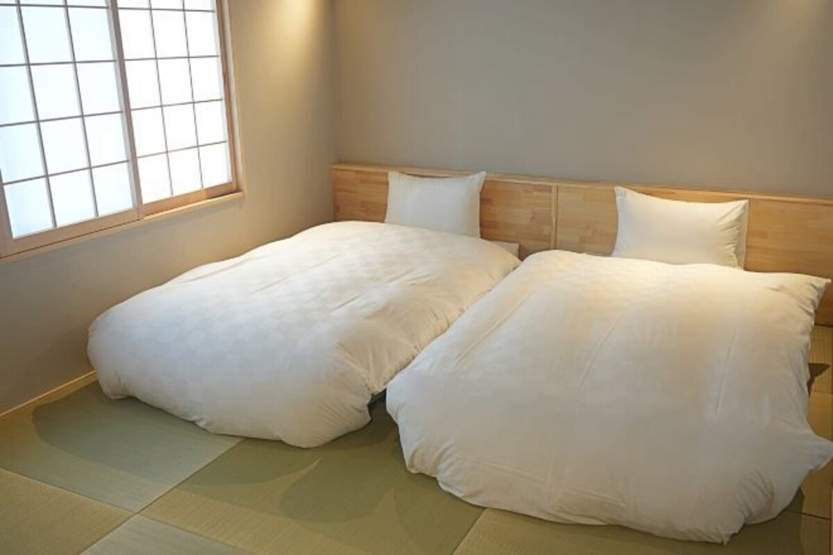A bedroom with two beds, a wooden headboard, and a window with a grid pattern.