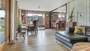 Ein geräumiges Wohnzimmer mit Ledersofa, Holzboden und einem Essbereich mit Tisch und Stühlen.