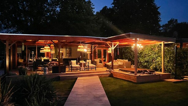 Eine moderne Außenpatio mit Holzboden, Sitzbereichen und stimmungsvoller Beleuchtung.