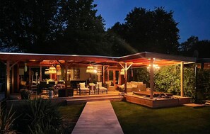 A modern outdoor patio with wooden flooring, seating areas, and ambient lighting. - Nice home in Erm with WiFi (Erm)