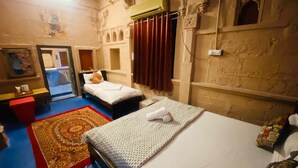 Habitación de hotel con dos camas, alfombra roja, un espejo y una pared con detalles arquitectónicos.