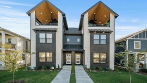 Un immeuble résidentiel moderne à deux étages, doté d’une entrée centrale, de grandes fenêtres et d’un toit en pente.