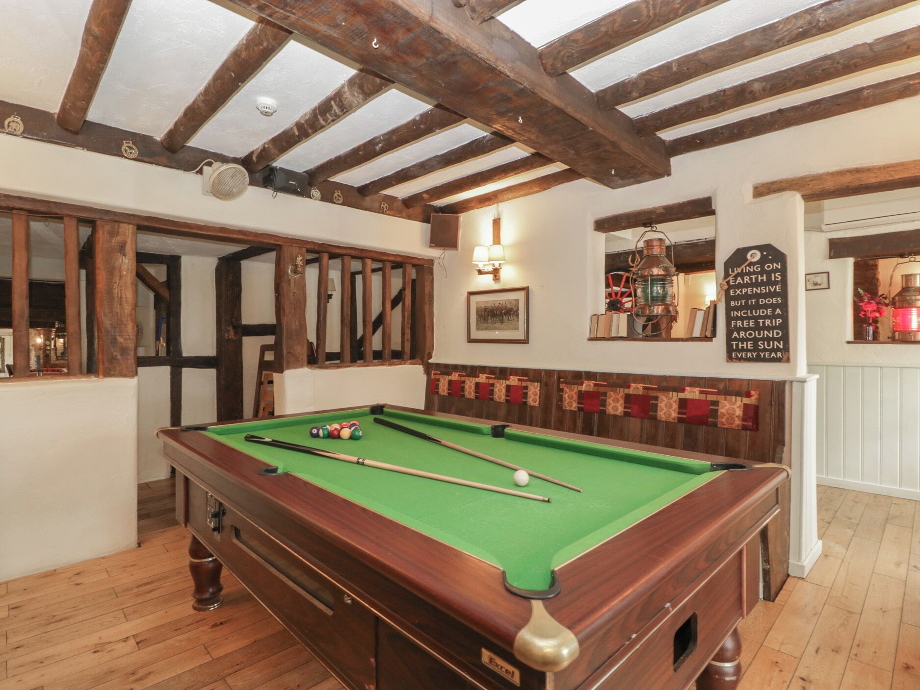 A pool table in a room with exposed wooden beams and a wall-mounted sign.