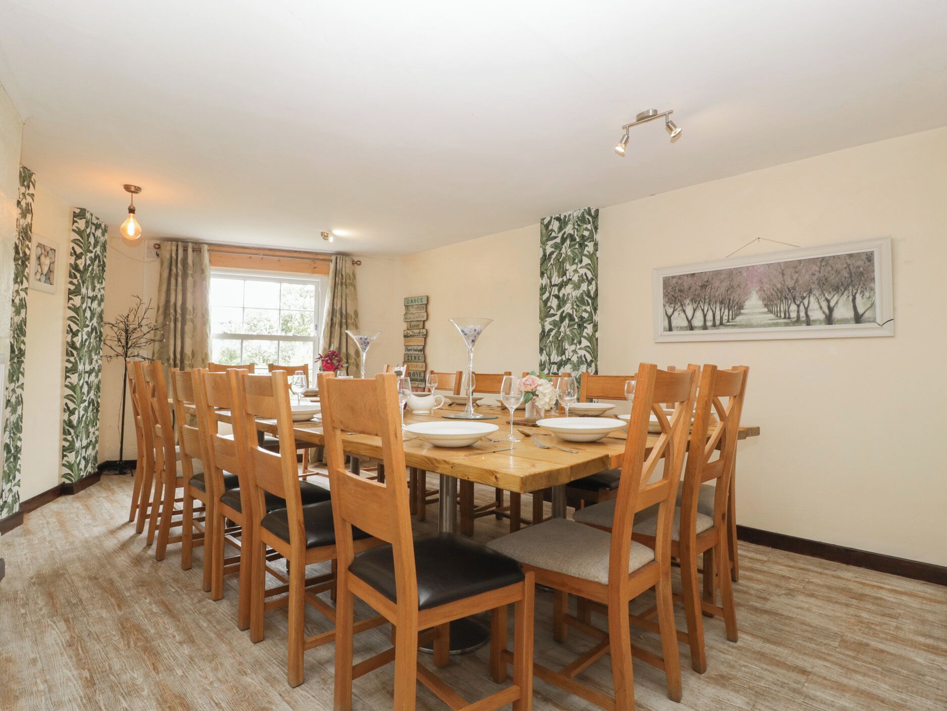 A dining area with a wooden table set for six, surrounded by wooden chairs with cushioned seats.