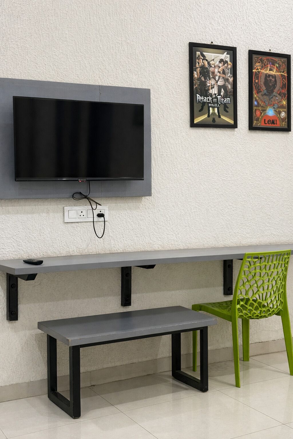 A modern room with a flat-screen TV mounted on the wall, a bench, and a green chair.