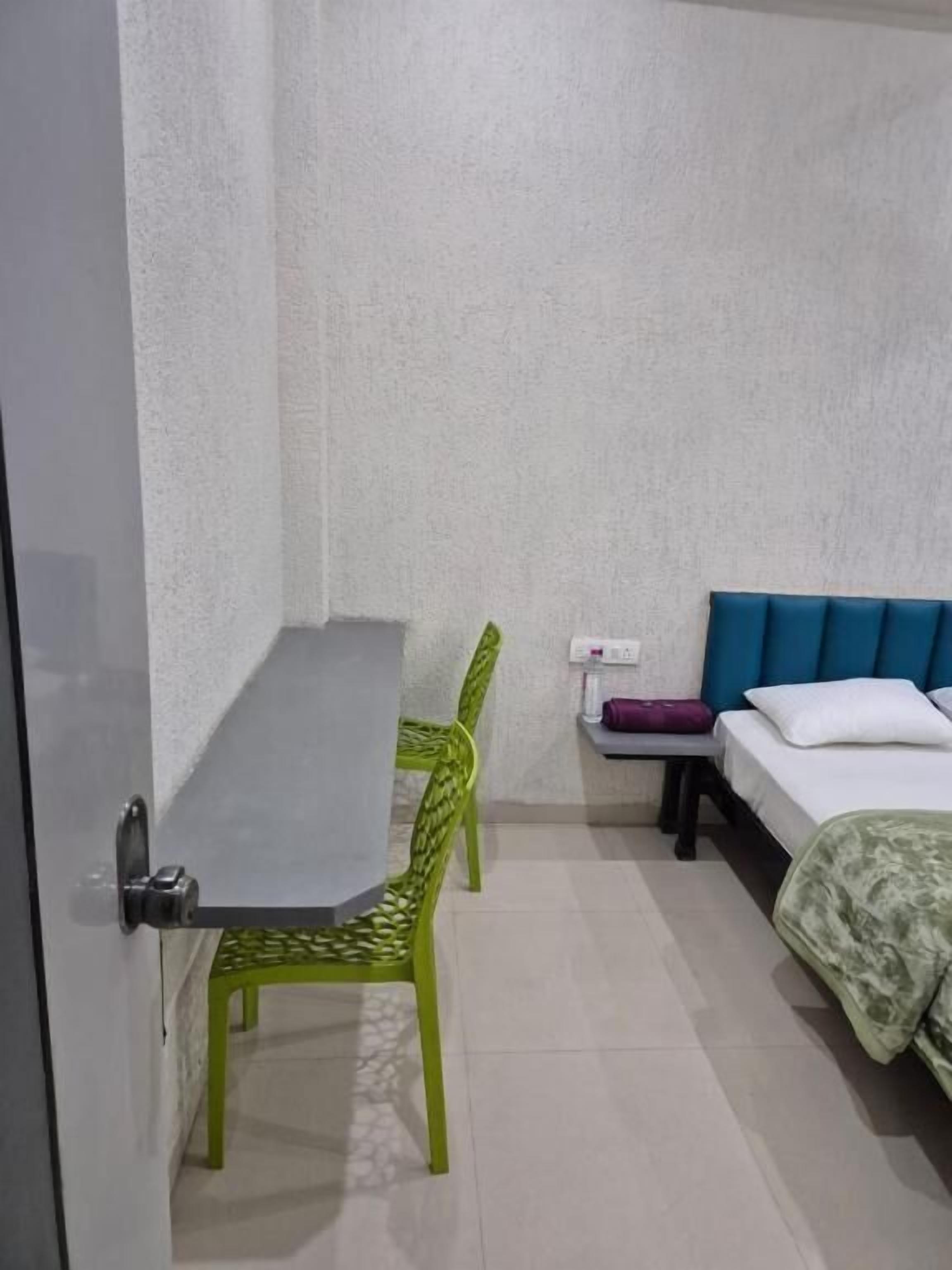A small, simple room with a bed, a table, and two chairs.