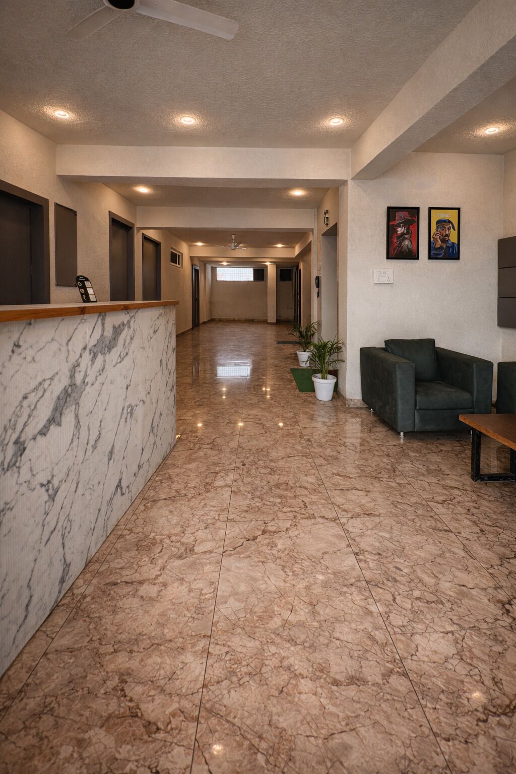 A hotel lobby with a marble reception desk, a green sofa, and a ceiling fan.