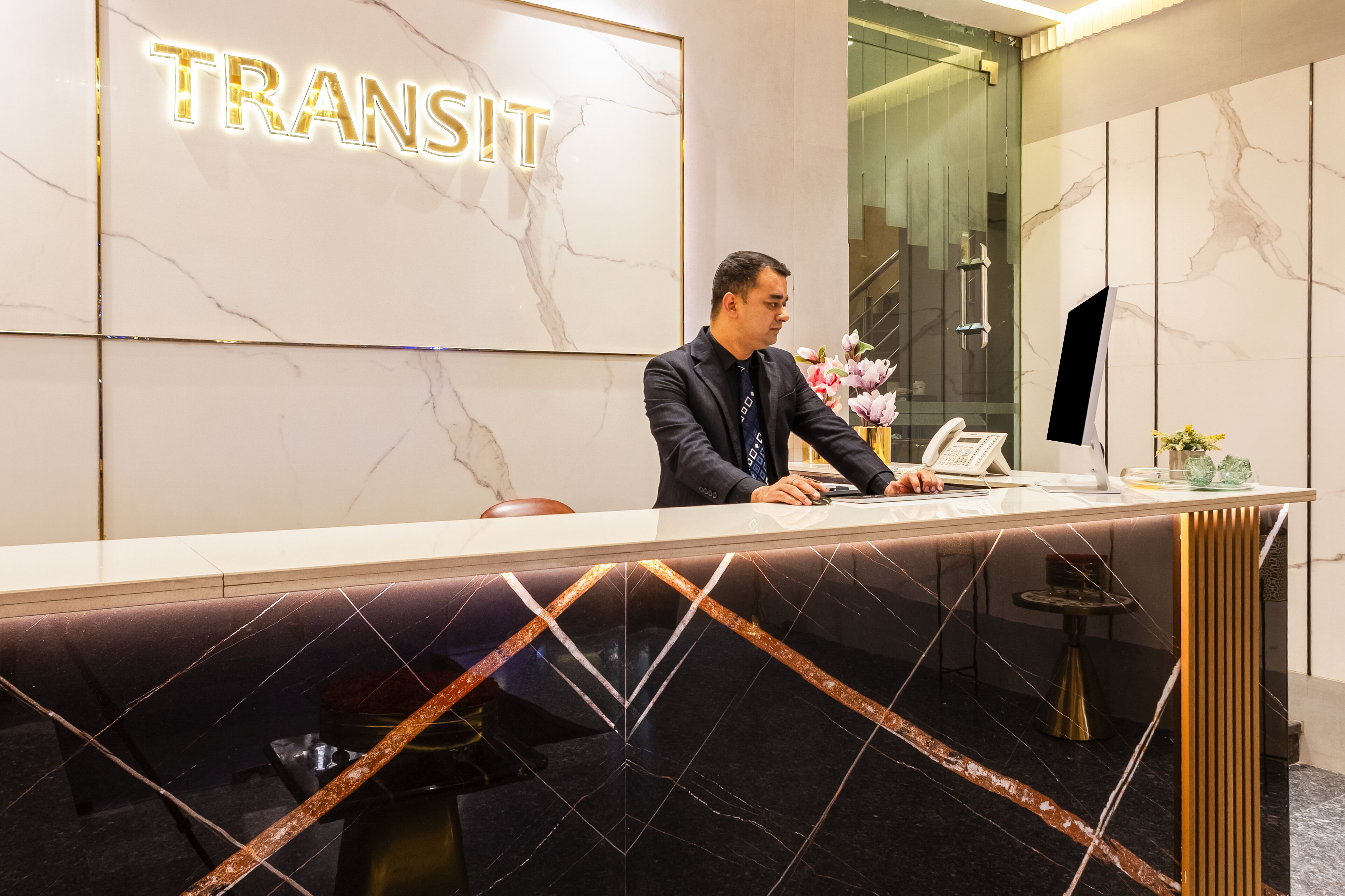 Un mostrador de recepción con una pared de mármol y un cartel que dice "TRANSIT".
