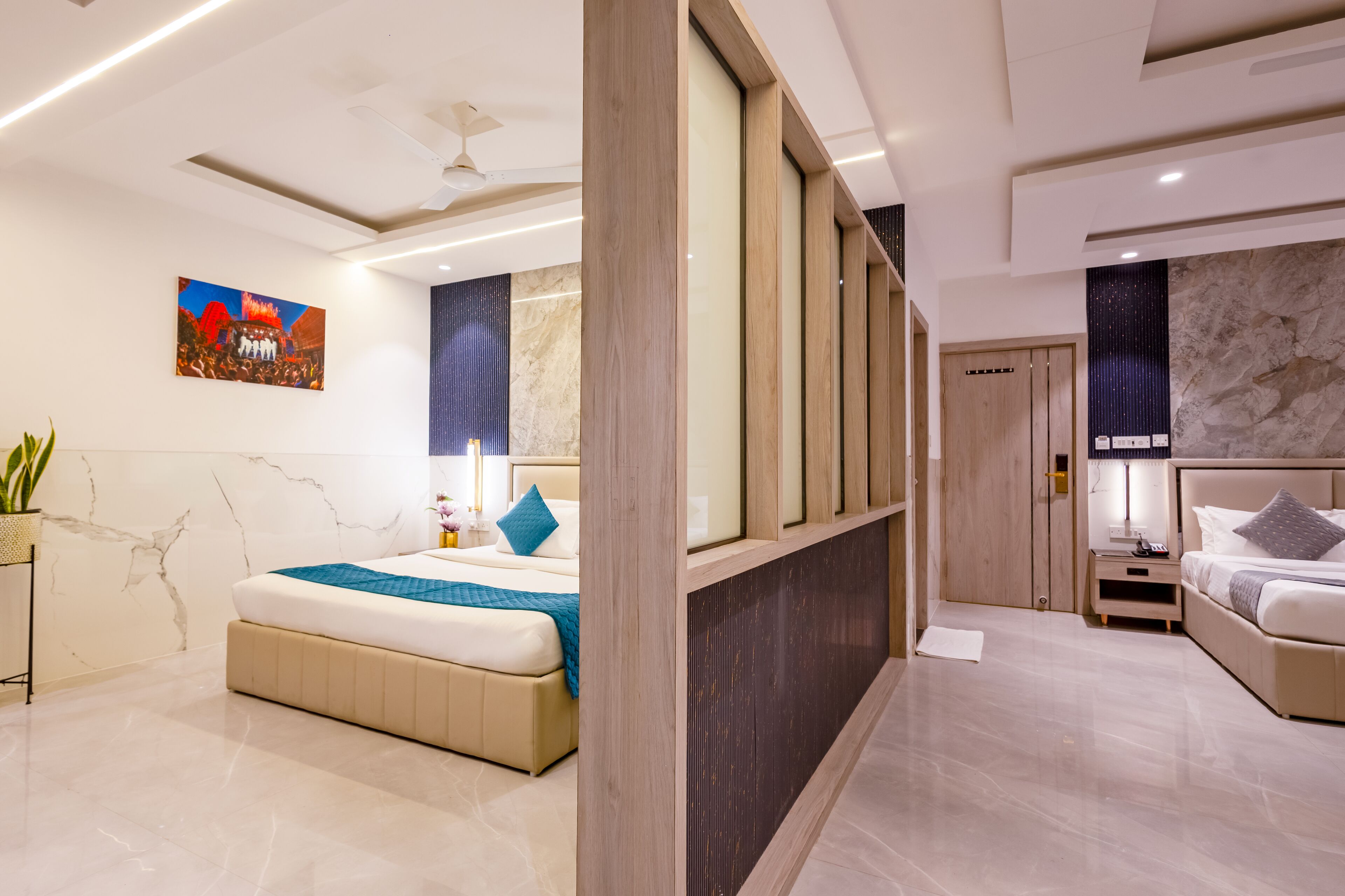 A modern hotel room with a large bed, a bedside table, a nightstand, and a painting on the wall.