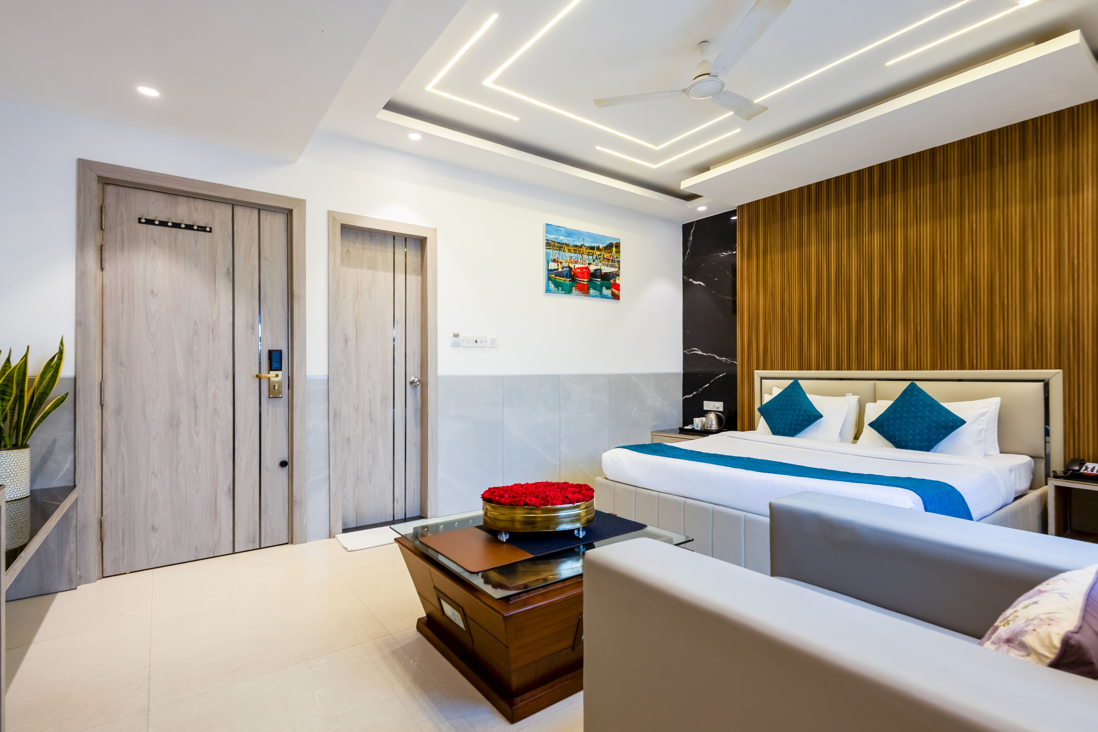 Quarto de hotel moderno com uma cama, uma escrivaninha, uma cadeira e uma pequena mesa com um objeto decorativo.
