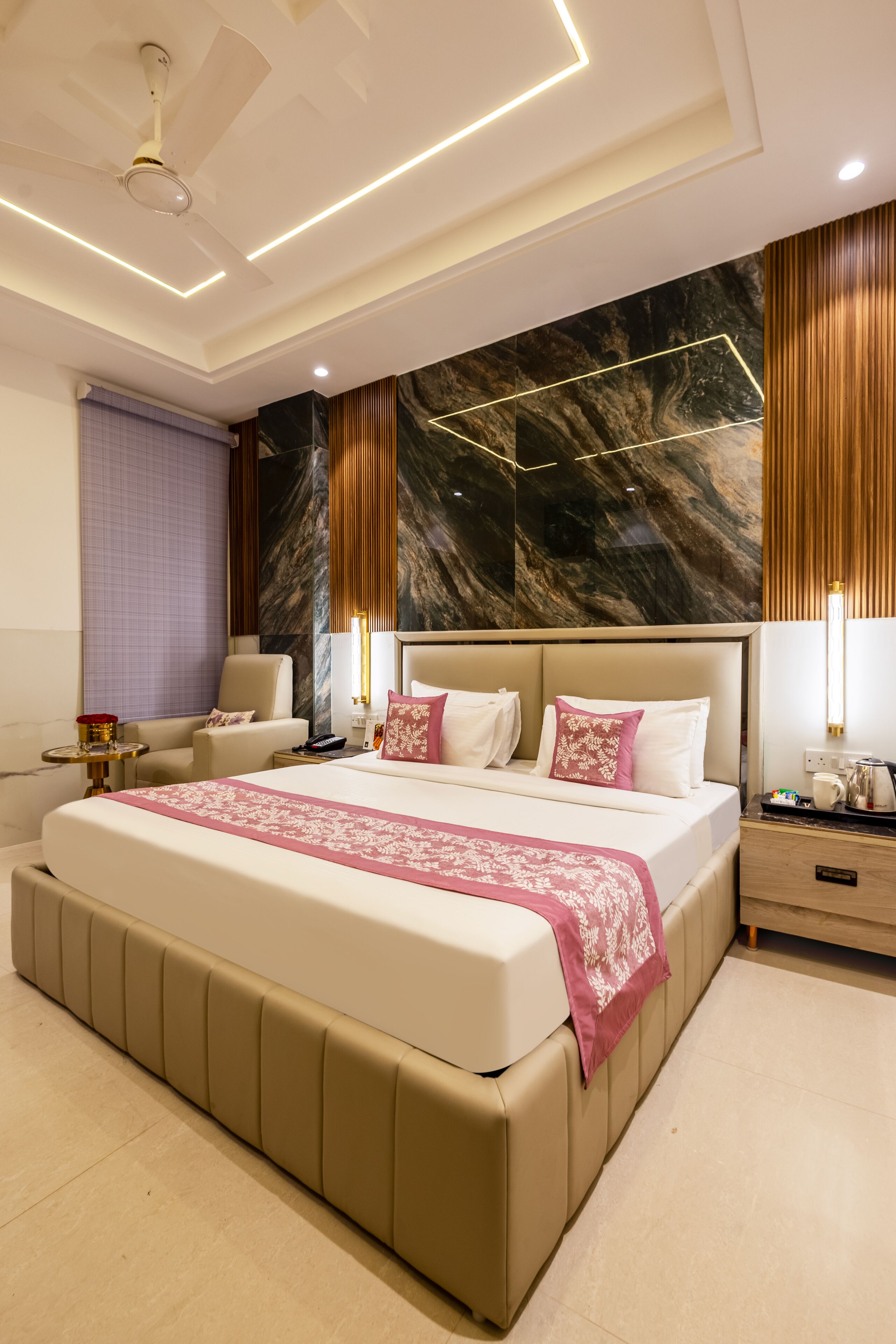 A modern bedroom with a large bed, a nightstand, a chair, and a ceiling fan.