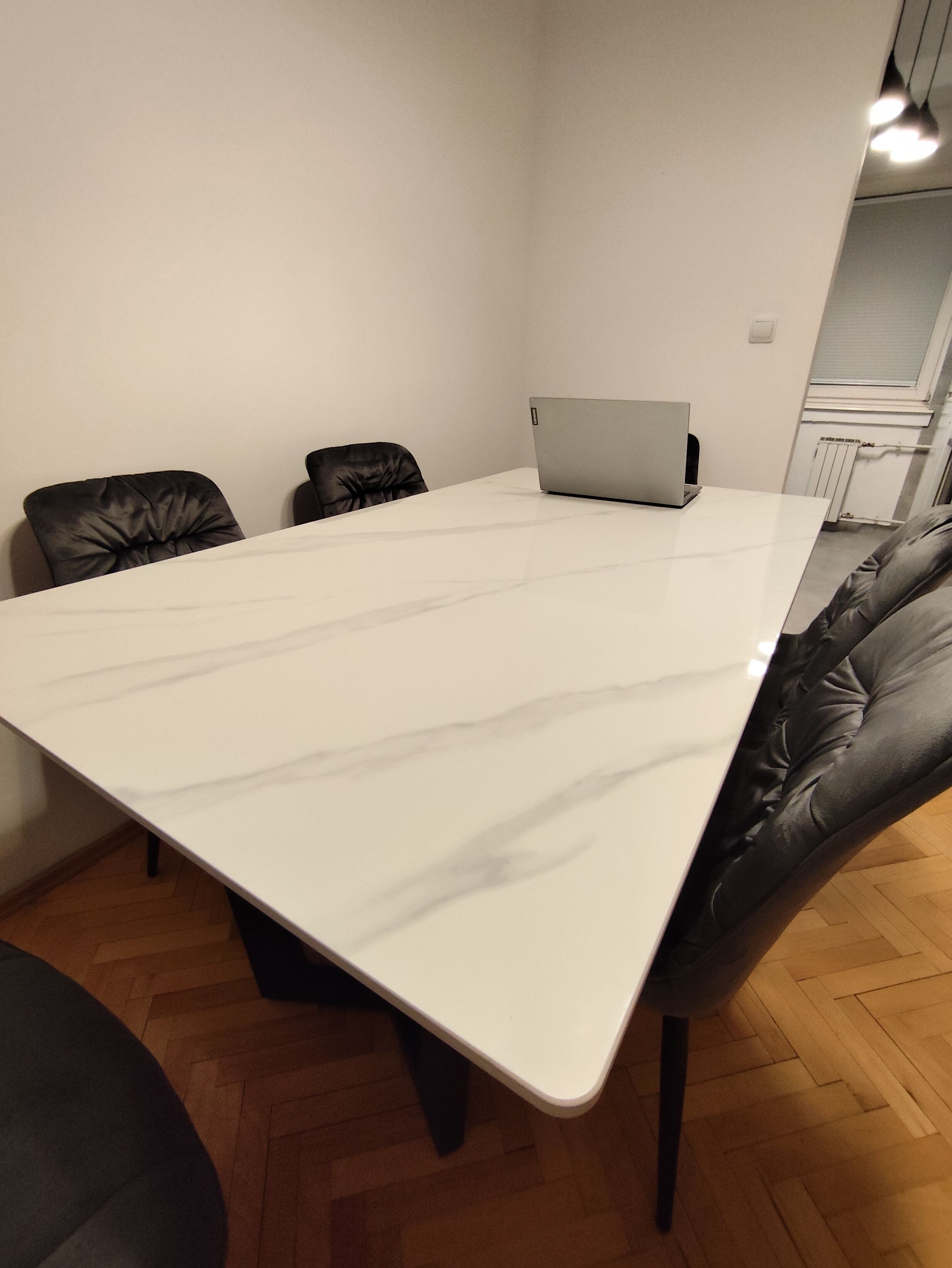 Ett konferensrum med ett stort vitt bord, svarta läderstolar och en bärbar dator på bordet.