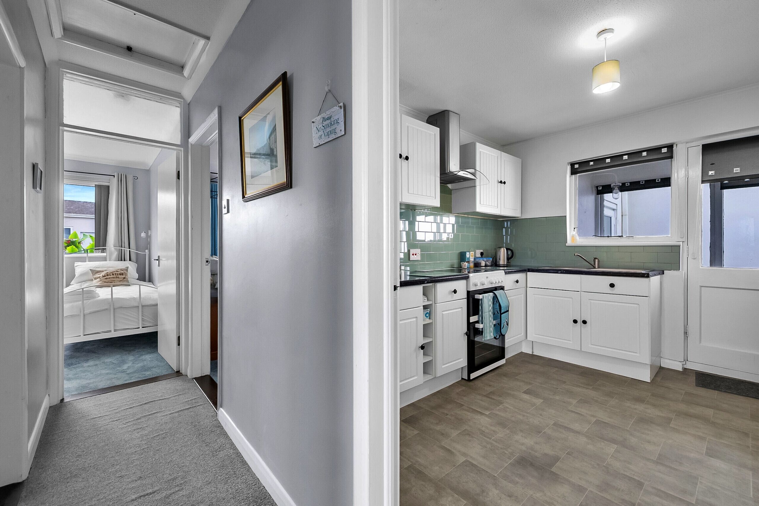 A modern kitchen with white cabinets, a stove, and a window.