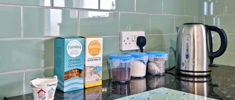 A kitchen counter with a box of Cornish Shortbread, a teapot, and containers of flour and sugar.
