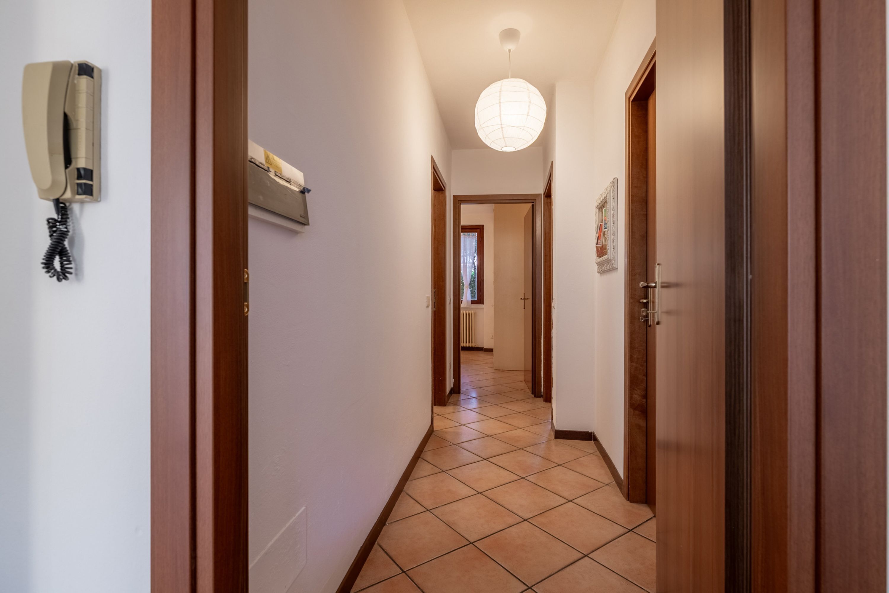 A hallway with a telephone, a light fixture, and a door.