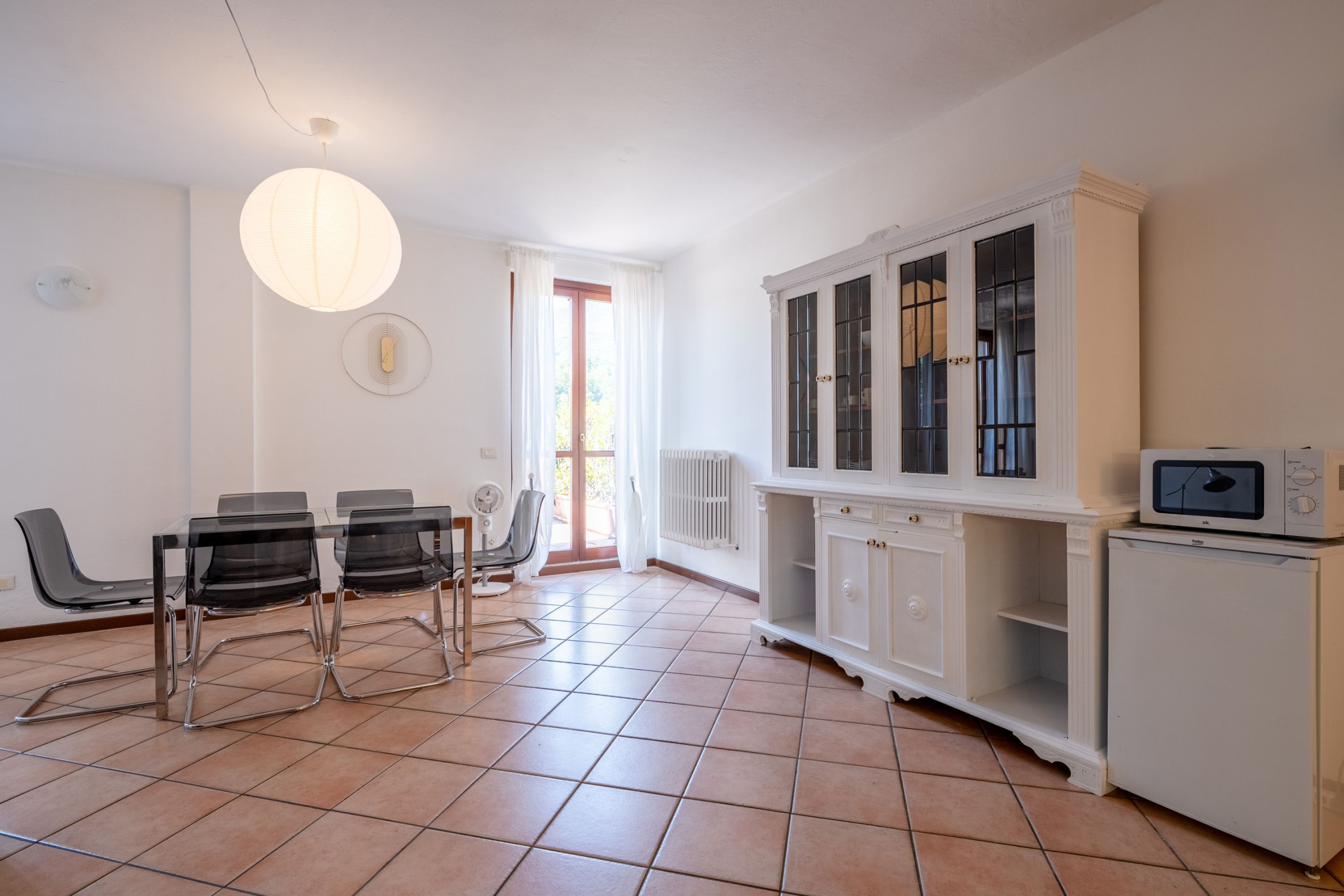 A modern kitchen with a dining area, white cabinetry, and a built-in microwave.