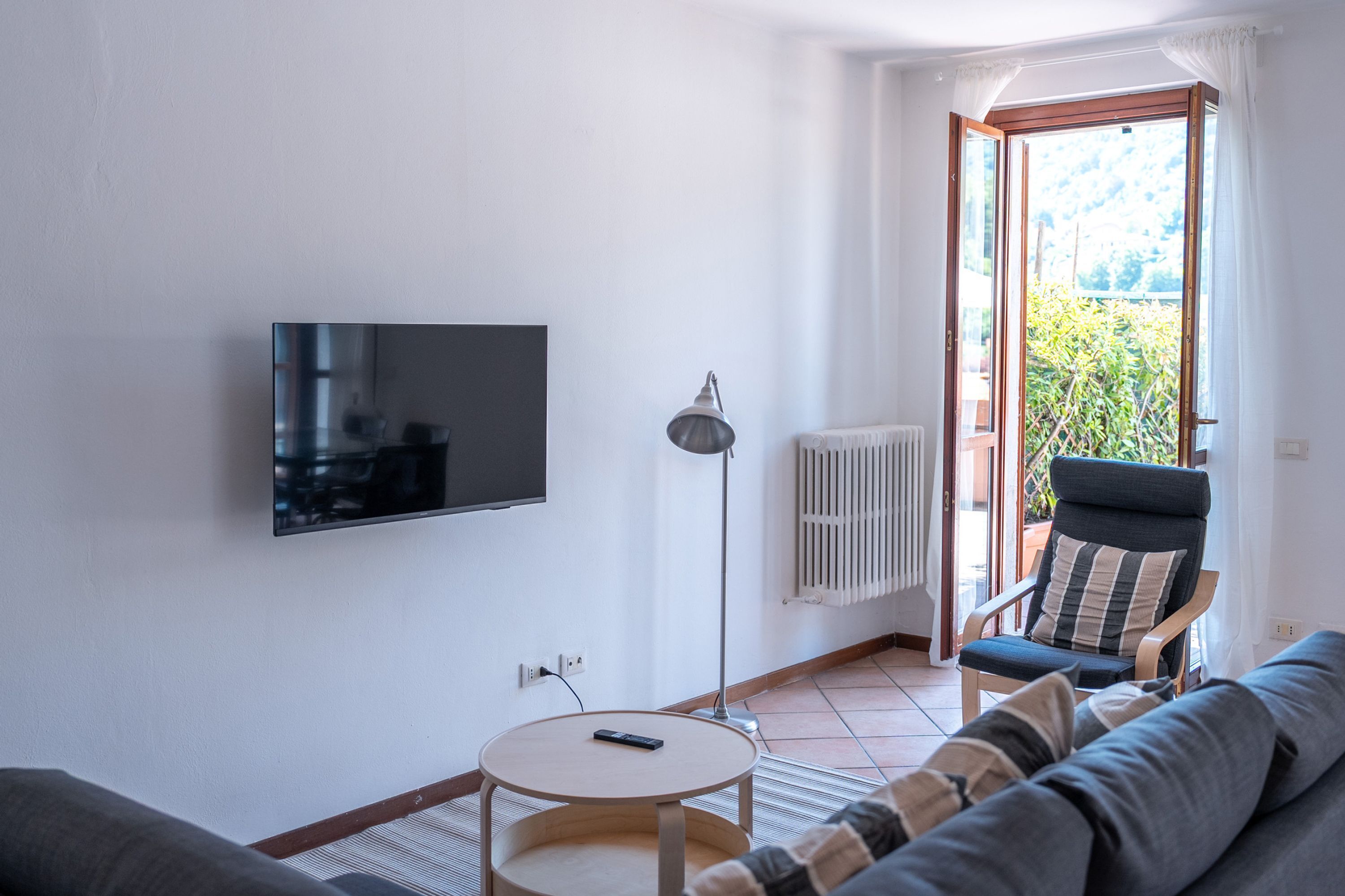 A living room with a TV, a round table, a chair, and a sofa.