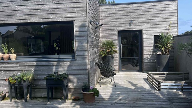 A modern wooden house with a deck, large windows, and potted plants. - 150 m² wooden family house with 3 terraces, close to the sea and surf spots! (Landunvez)