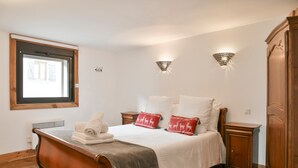 Une chambre à coucher avec un lit en bois, deux tables de chevet, une fenêtre et des lampes fixées au mur.