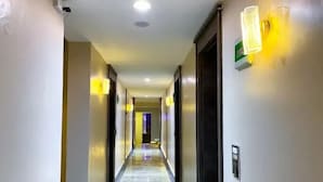 En hotellkorridor med ett marmorgolv, ljusa väggar och moderna lampor.