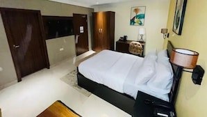 Ett modernt hotellrum med en stor säng, ett skrivbord, en stol och en garderob.