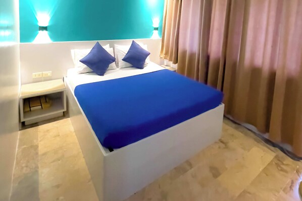 A modern hotel room with a large bed, a bedside table, and a nightstand. - Legazpi Tourist Inn (Legazpi)