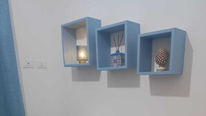 A white desk with a lamp and a decorative item, flanked by blue shelves with small items. - The Carusians rent short (Marsala)