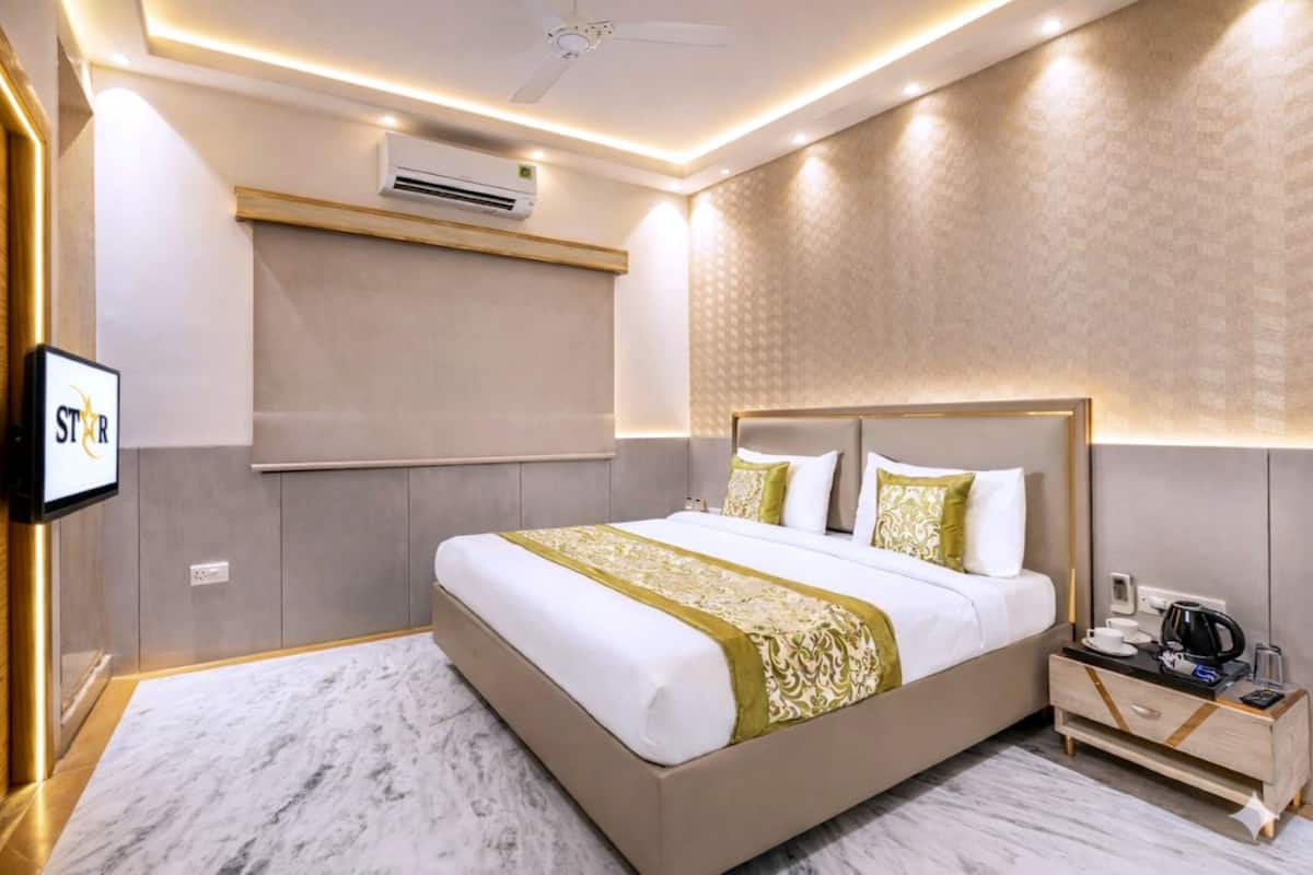 A modern hotel room with a large bed, bedside table, and a flat-screen TV.