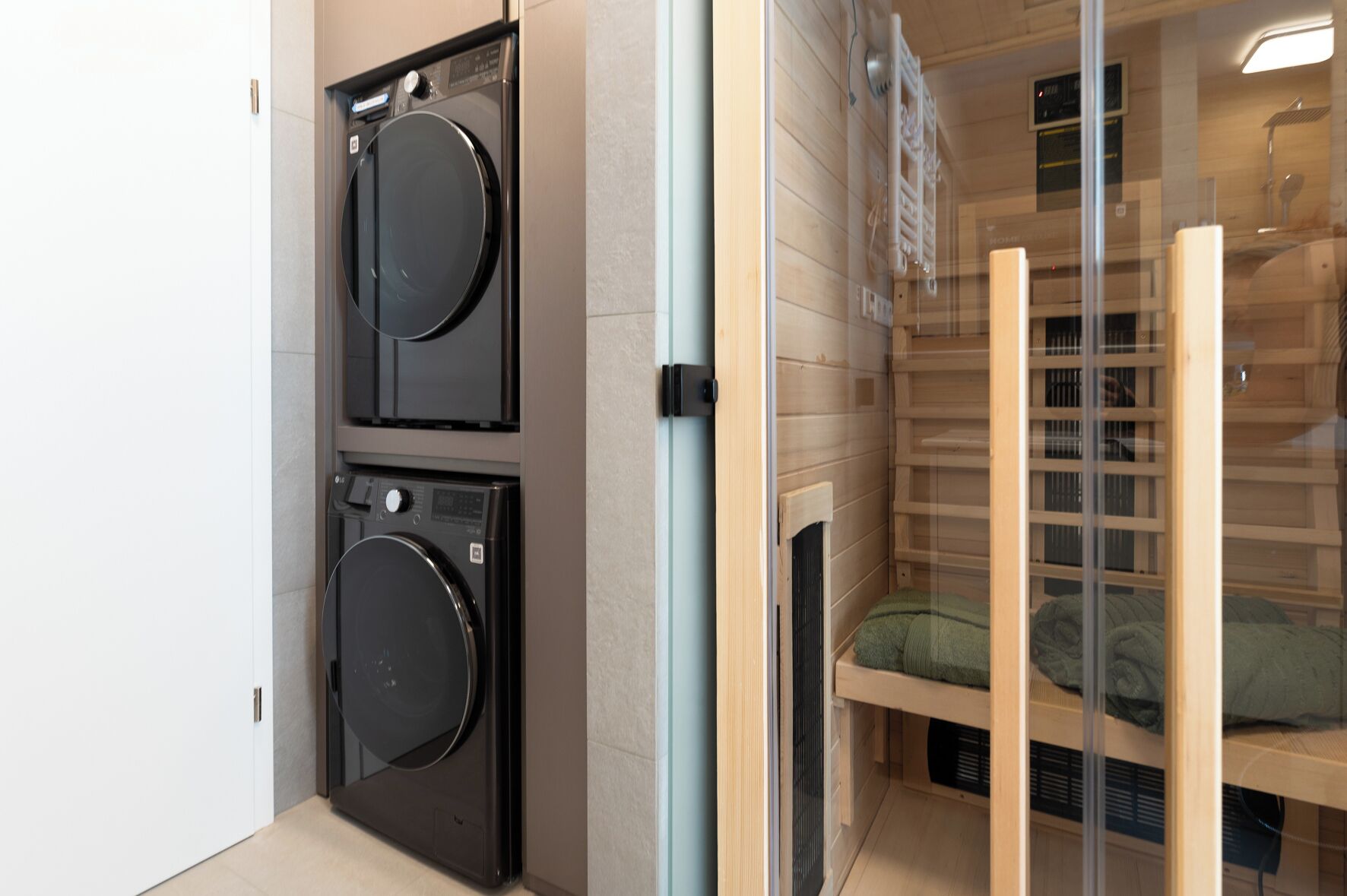 A laundry room with two stacked washing machines and a drying rack.