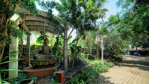 A garden with a Buddha statue, a pergola, and a pathway. - The Amore Collective (Bengaluru)