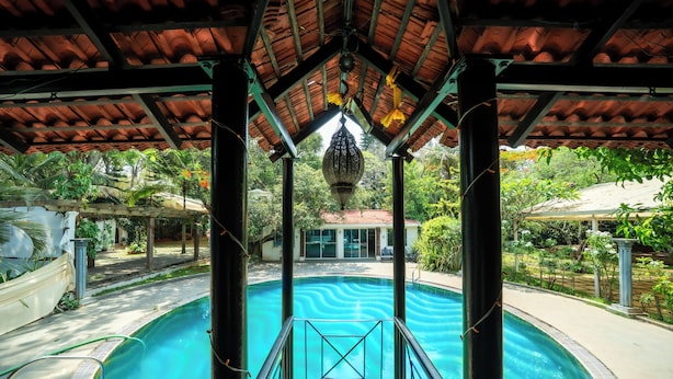 A swimming pool with a view of a building in the background. - The Amore Collective (Bengaluru)