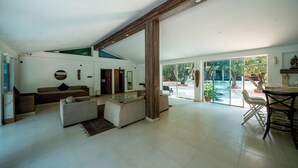 A spacious living area with a high ceiling, a large window, and a dining area with a table and chairs. - The Amore Collective (Bengaluru)