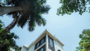 A two-story building with a white facade, large windows, and a balcony with blue railings. - The Amore Collective (Bengaluru)