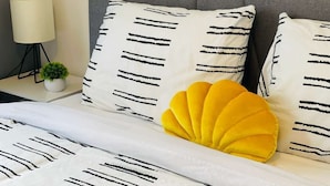 A bed with white bedding and black stripes, a yellow accent pillow, and a grey headboard. - TopUnit Floor Near Airport One bedroom (Cleveland)