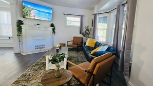 Un salon moderne avec une cheminée, un téléviseur fixé au mur et un canapé agrémenté de coussins.