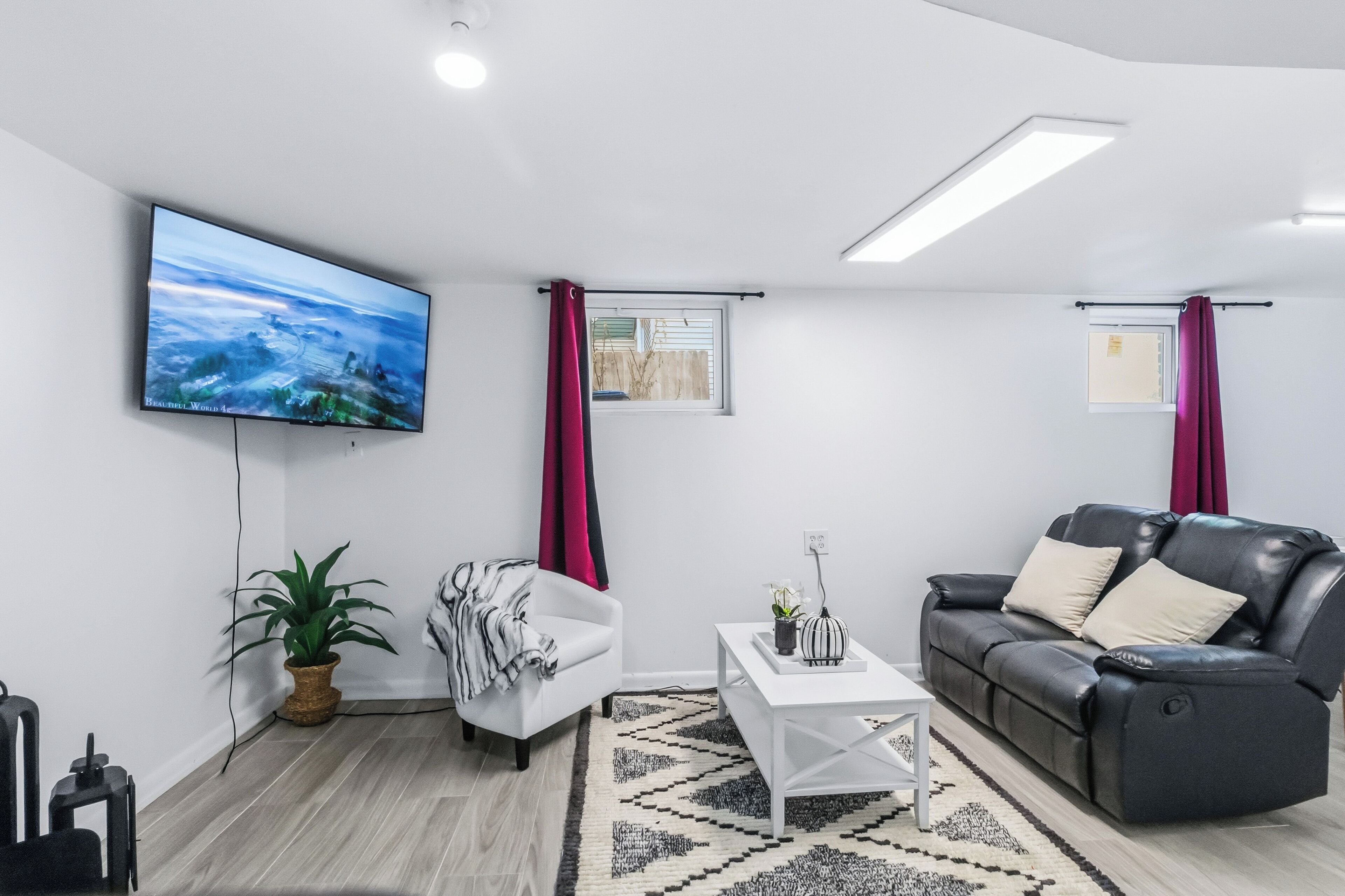 Un saló modern amb televisió de pantalla plana, un sofà, una poltrona blanca, una taula de centre i una planta en test.