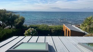 A terrace with a view of the sea, wooden deck, and a glass enclosure. - Seaside Chalet with Direct Water Access (Fermanville)