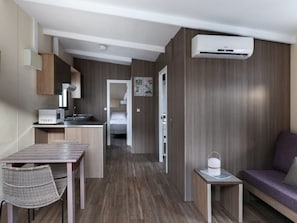 A compact hotel room with a kitchenette, a dining area, and a seating area.