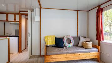 Une pièce de taille modeste, avec un lit en bois, une petite kitchenette et une fenêtre donnant sur un paysage agréable.