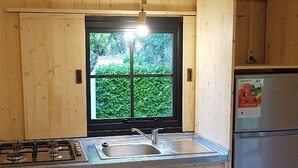 A kitchen with wooden cabinets, a gas stove, a sink, and a refrigerator. - Stilt house with terrace for 2 guests (Moncrabeau)