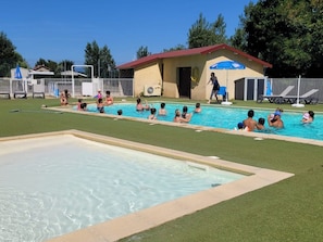 A swimming pool with multiple lanes, a lifeguard stand, and a small building with a red roof.