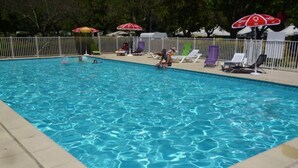 Une piscine à l’eau d’un bleu limpide, entourée de chaises longues et de parasols.