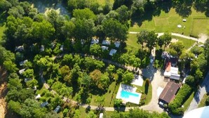 Vue aérienne d’un quartier résidentiel avec une piscine, entouré d’une végétation luxuriante et d’arbres.