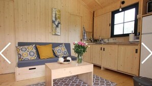 Un intérieur de chalet chaleureux avec un canapé, une table basse et un coin cuisine.